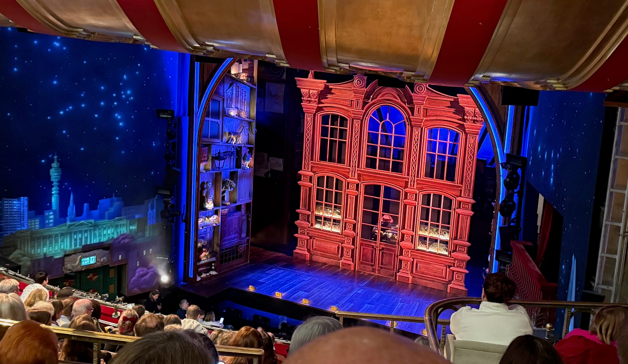 A view of the stage at the Savoy Theatre. The set is a shopfront with a red hat visible.